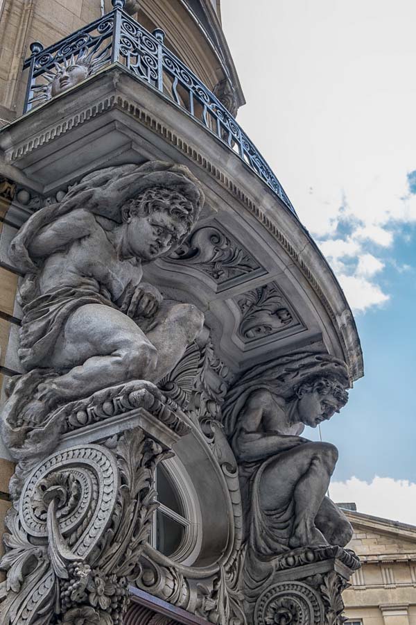 grey stone carving of mythical creatures on exterior of building