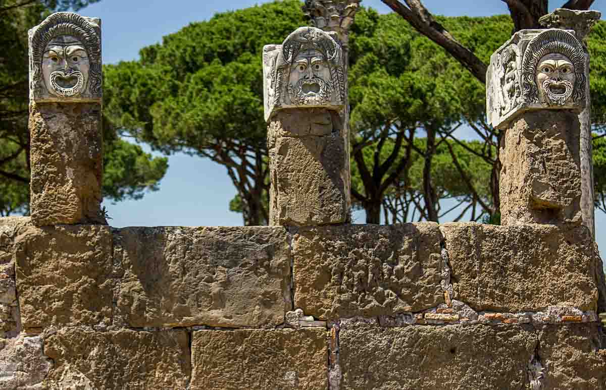 stone heads on top of columns at the ancient roman site of ostia antica visited as a day trip from rome