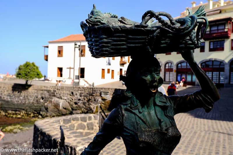 bronze sculpture of a woman with a basket on her head