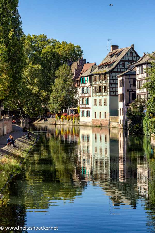 two people sitting on bank of pretty canal in strasbourg france