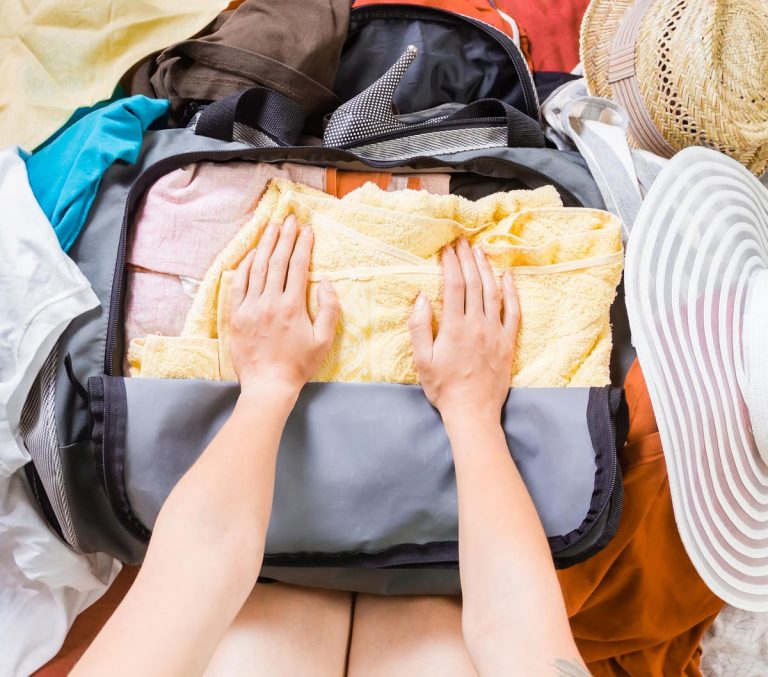 woman trying to pack light for a holiday by pressing items into her hand luggage