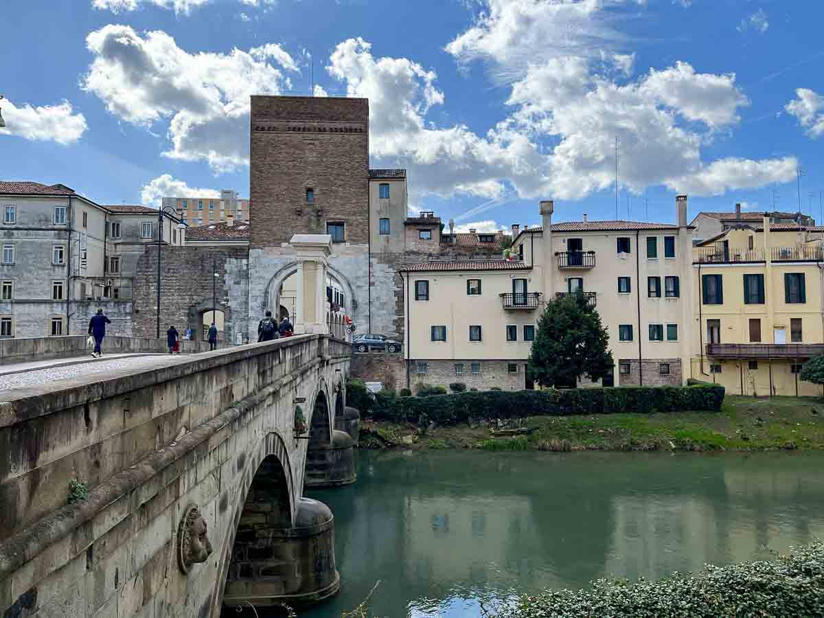 people walking across an old stone bridge in padua in italy