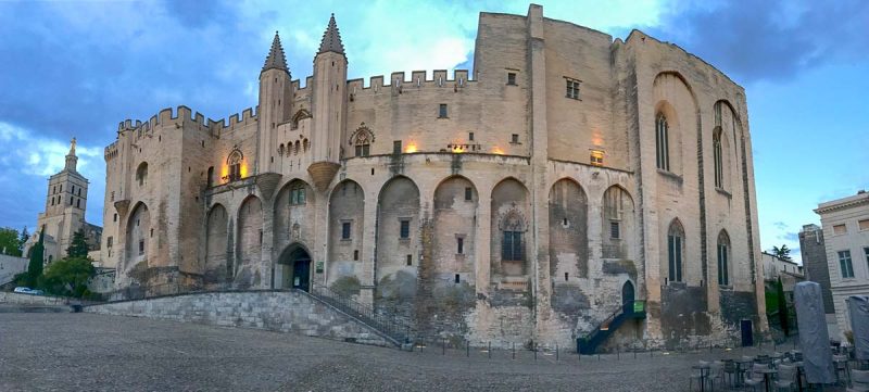 beige stone exterior of palais des papes on a sunny evening