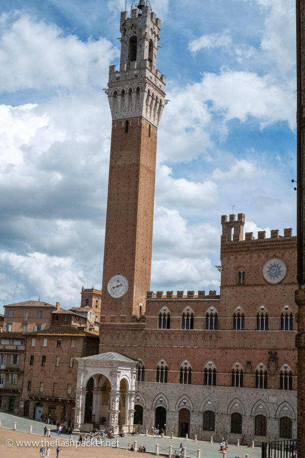 facade of crenellated palazzo publico in siena with tall bell tower