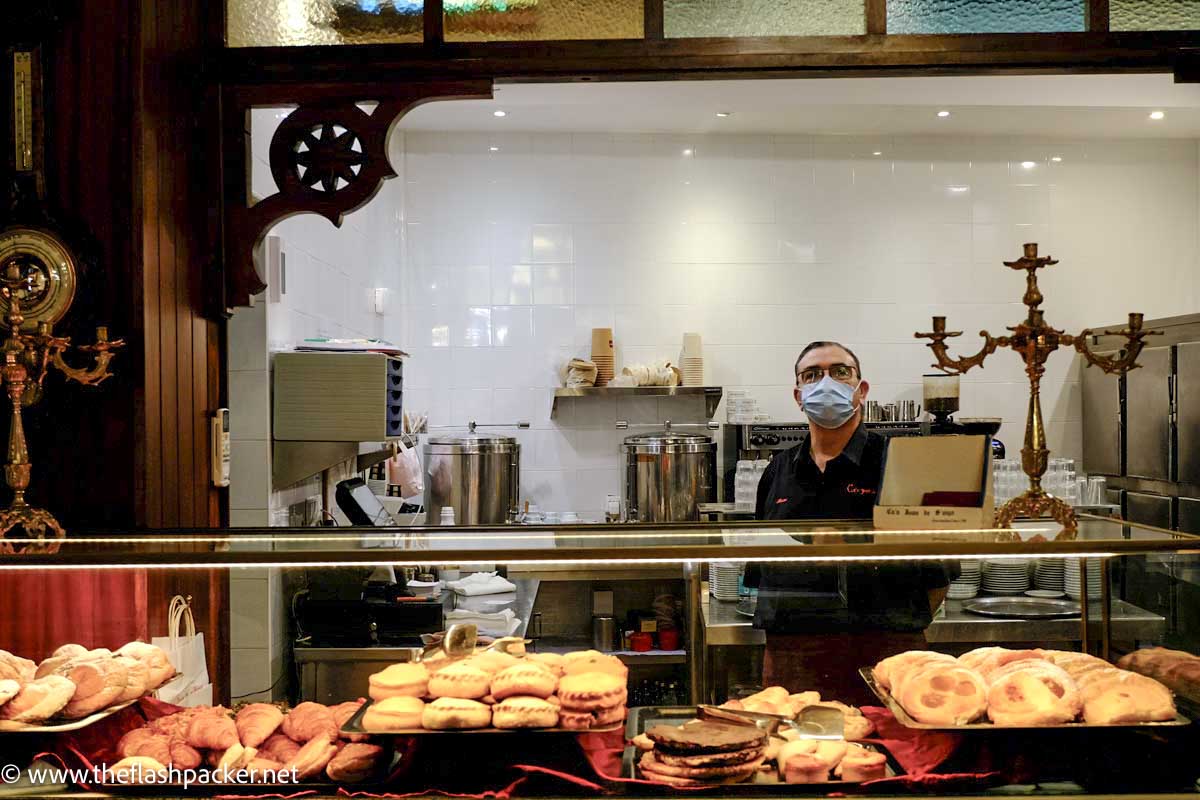 man standing behind cabinet of pastries