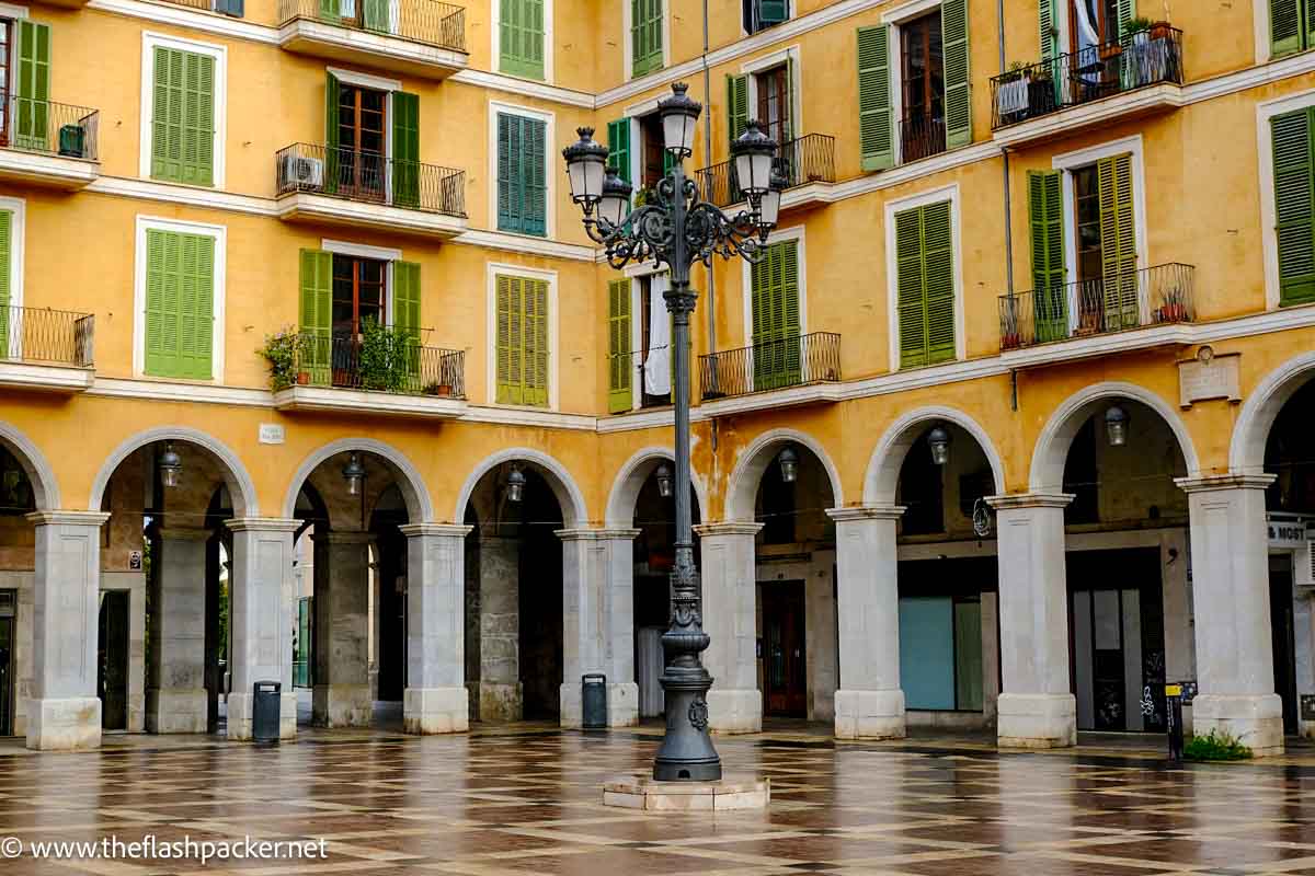 plaze in palma de mallorca spina with graceful arcaded yellow buildings with green shutters