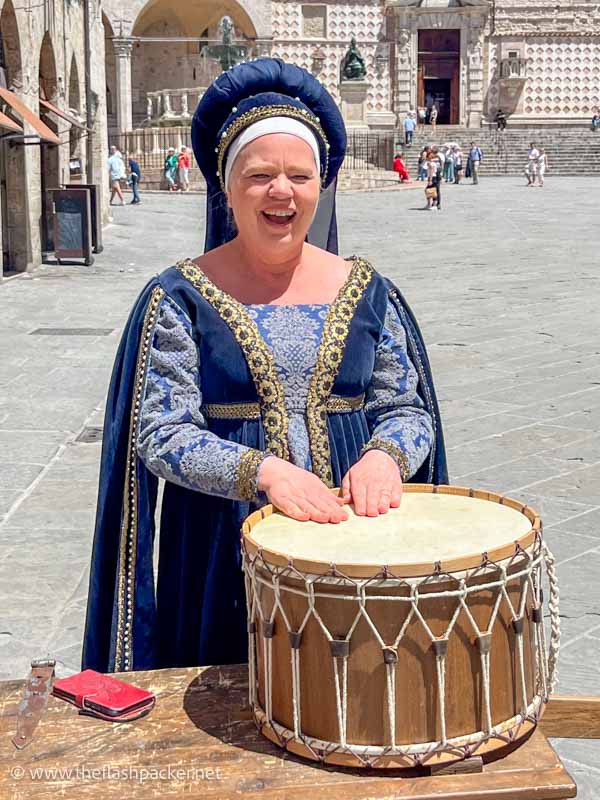 woman in medieval costume banging a small drum