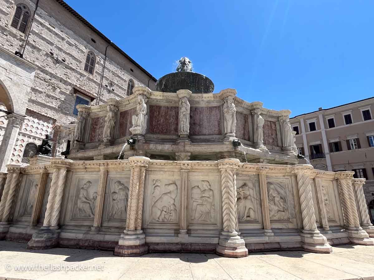 ornate circular fountain with carved panels and small statuettes