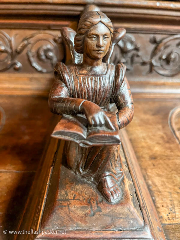 wooden carving of a woman reading a book