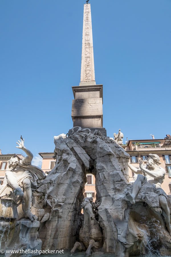 obelisk behind baroqye sculpted figures of fountain in piaza navona in rome italy