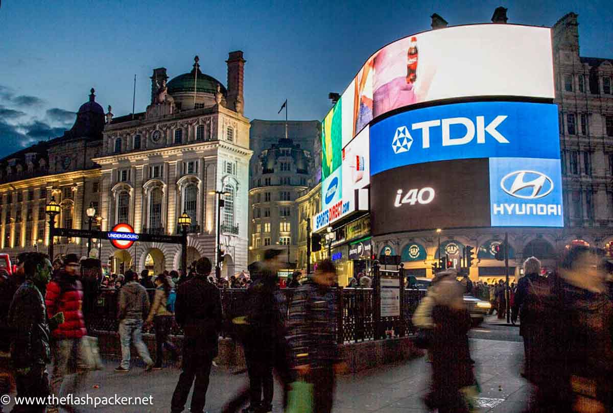 piccadilly circus at night with neon billboard and entrance to tube station