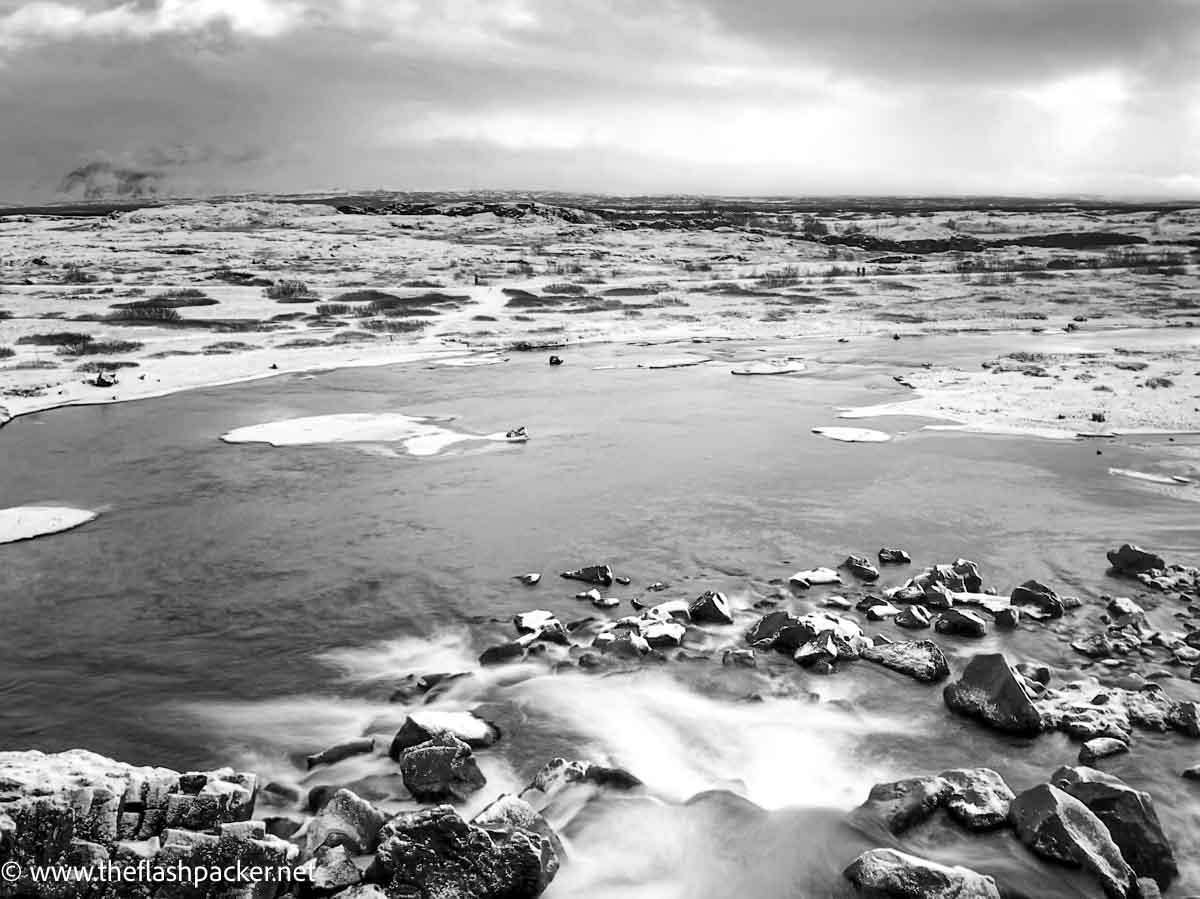 rocks in glacial lake with snow topped mountain