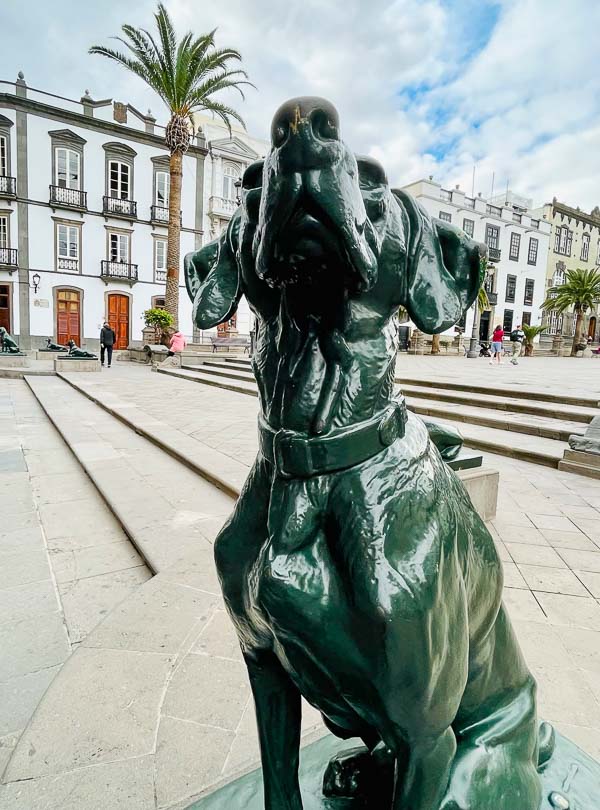 bronze sculpture of a dog in a colonial plaza