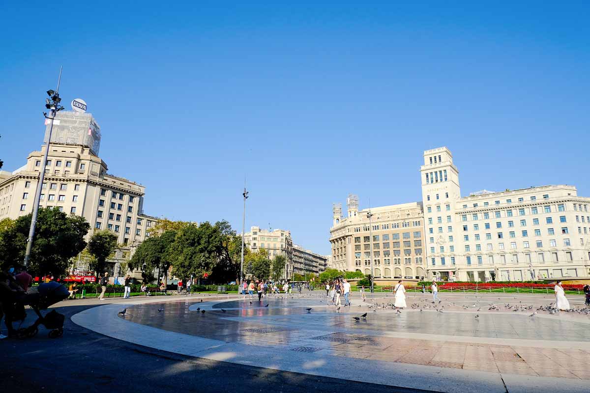 massive empty plaza flanked by two large buildings under blue sky