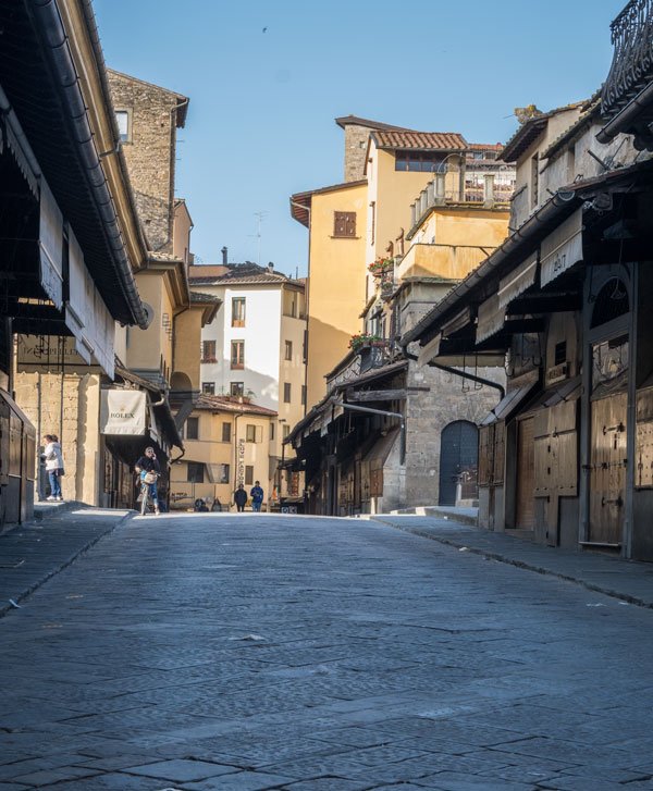 a few people on ponte vecchio bridge in florence in early morning