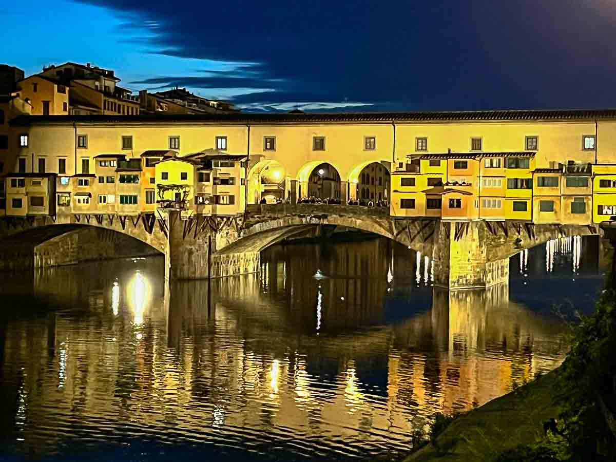 the ponte vecchio bridge lit up at night under a dark sky