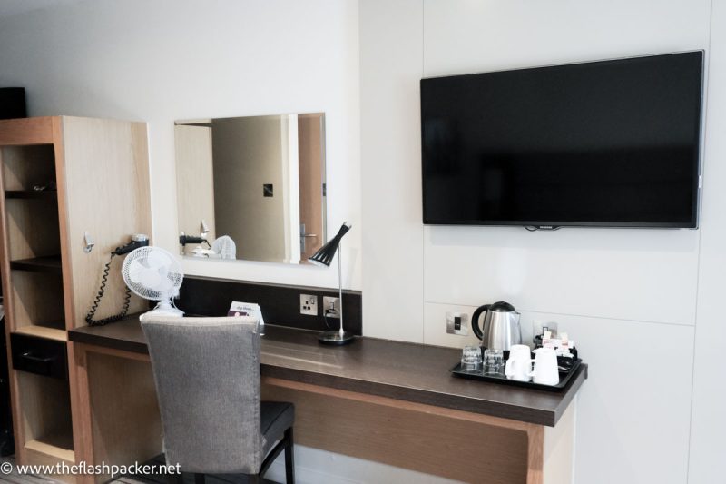 desk in hotel room with lamp and desk fan