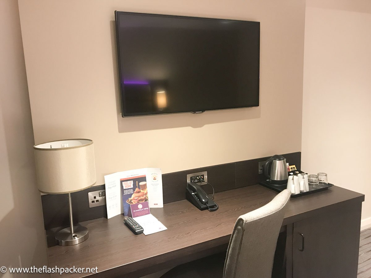 chair and desk with tv on wall in premierr inn london heathrow terminal 4 room