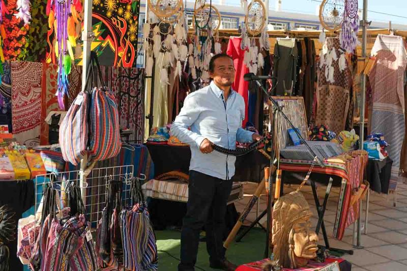 man playing pan pipes in a a market stall