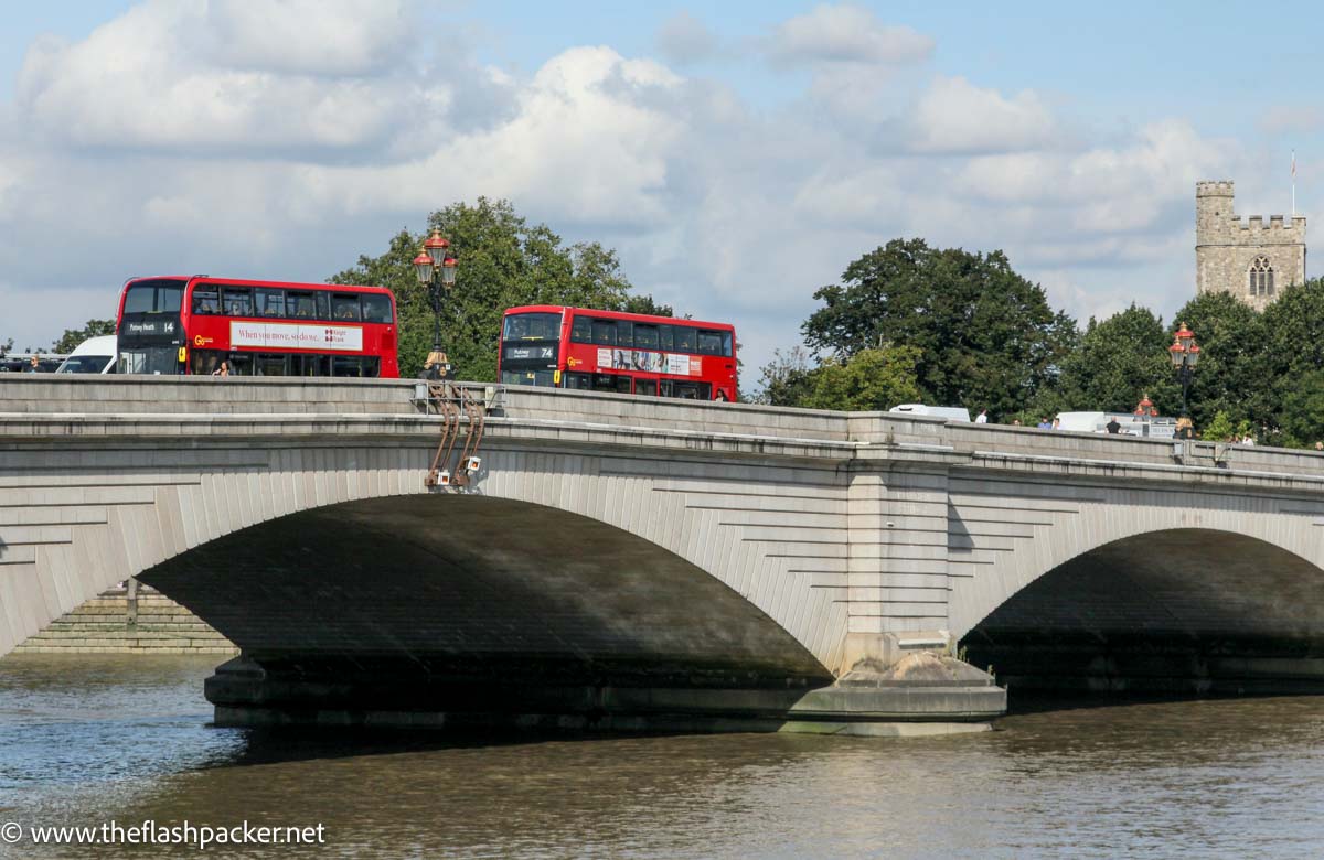 two red buses on stone bridge over river thames in london