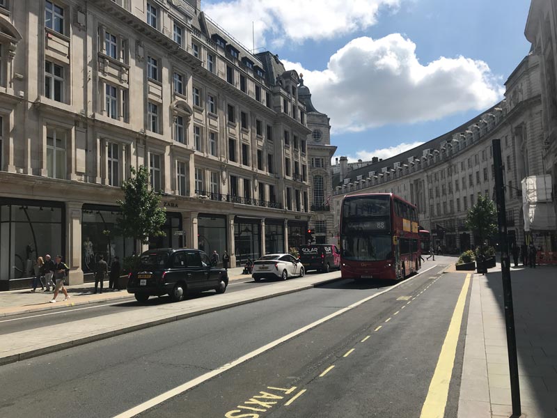 red bus and taxi on one of the streets of london