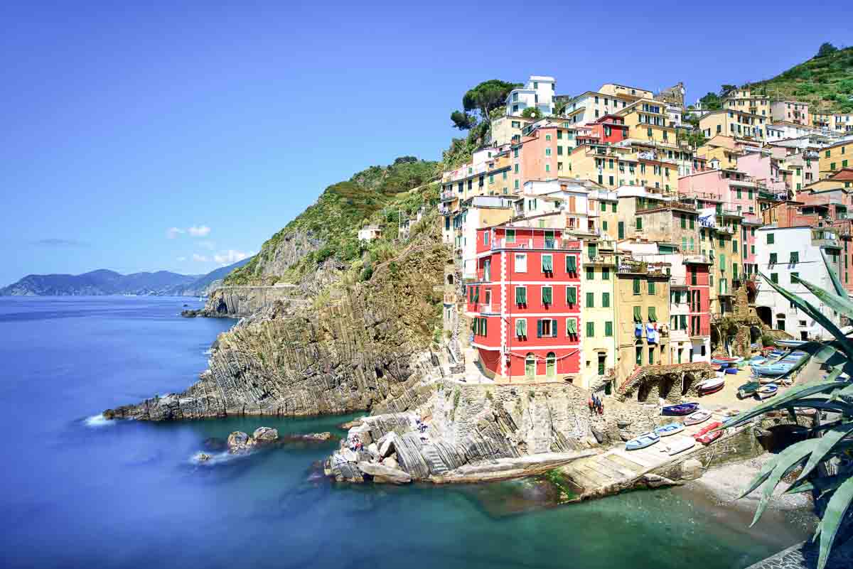 brightly coloured houses set on cliffside with deep blue sea