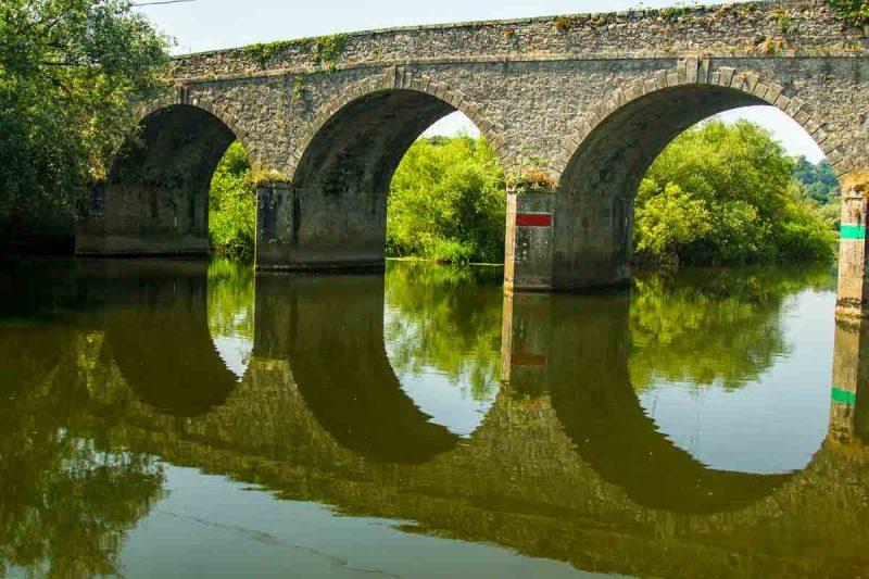 stone bridge with three arches over a still river