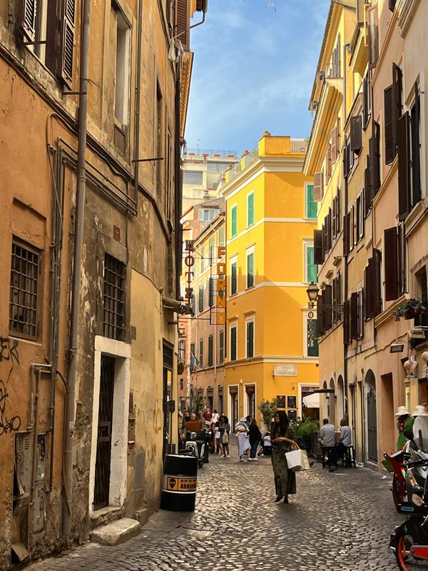 narrow cobbled street in rome with ochre colour buildings