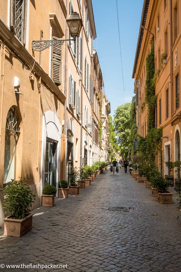 narrow street in rome with cobblestones and ochre coloured buildings