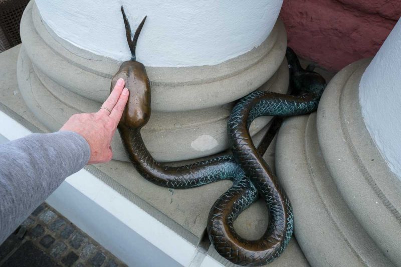 woman touching the bronze sculpture of a serpent