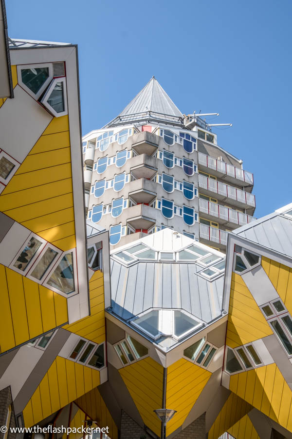 yellow geometric cube houses in rotterdam in front of pointed tall modern building