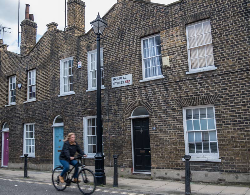 woman cycling along one of the old streets of london