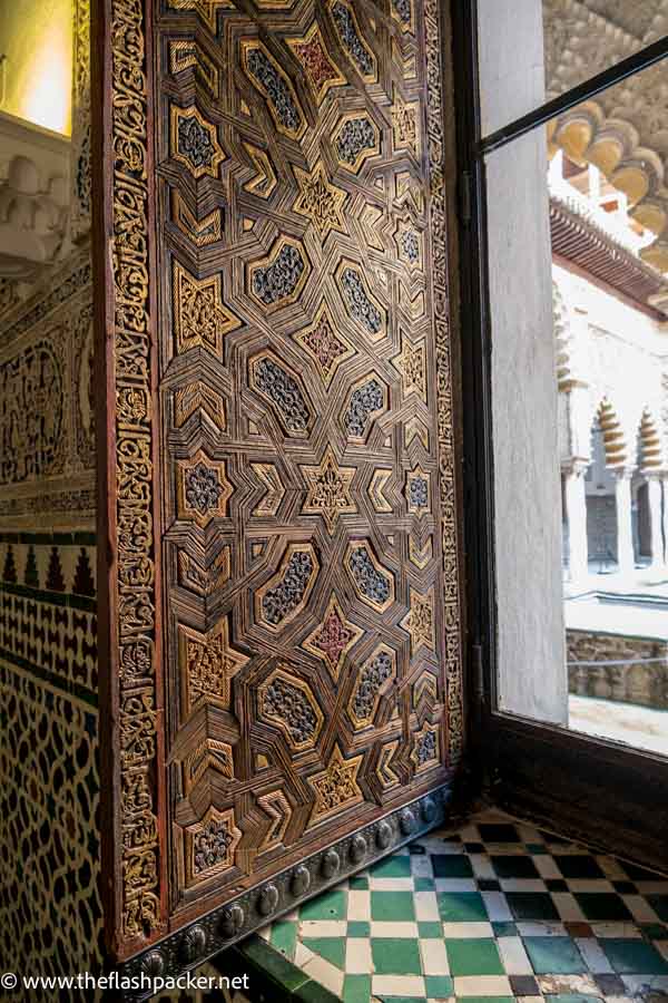 ornate wooden shutter with tiled windowsill and walls