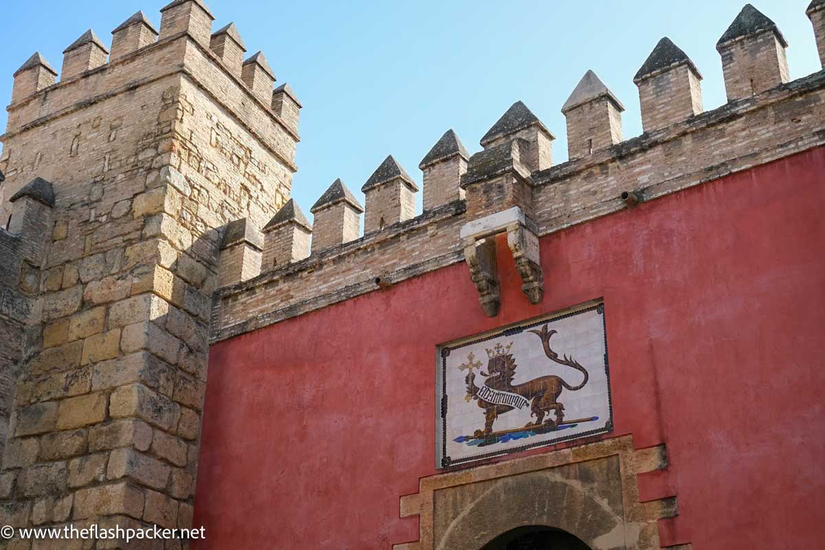 top of gateway to the royal alcazar of seville with the crest of a lion