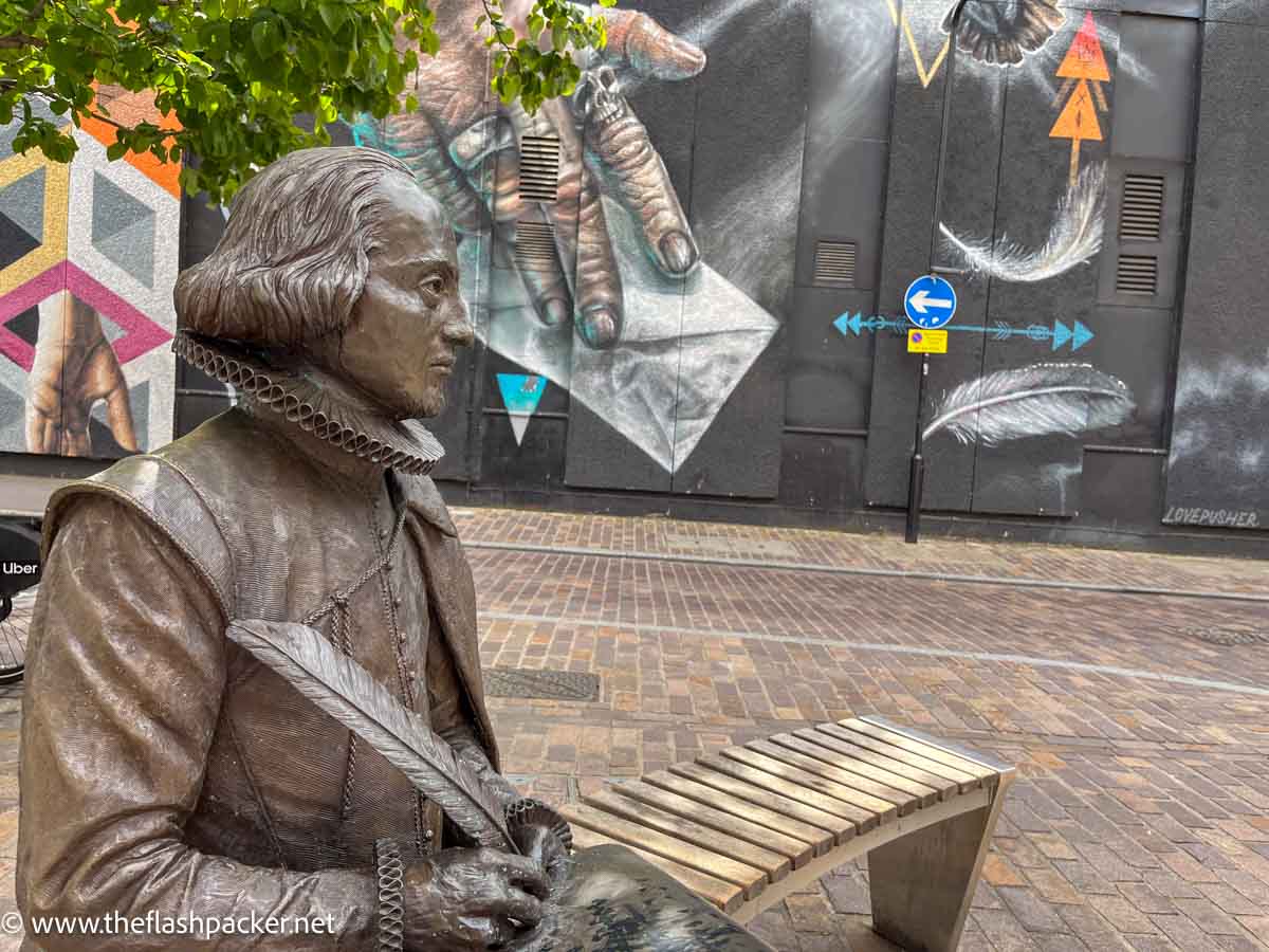 bronze statue of william shakespeare sitting on a bench