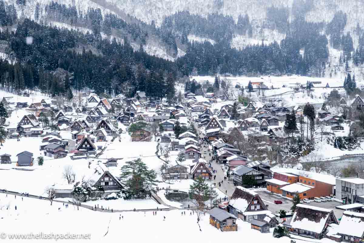 snow falling on a small village of a-shaped timber framed houses