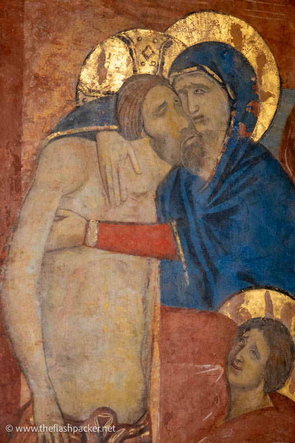 gilded fresco of mary cradling a crucified jesus