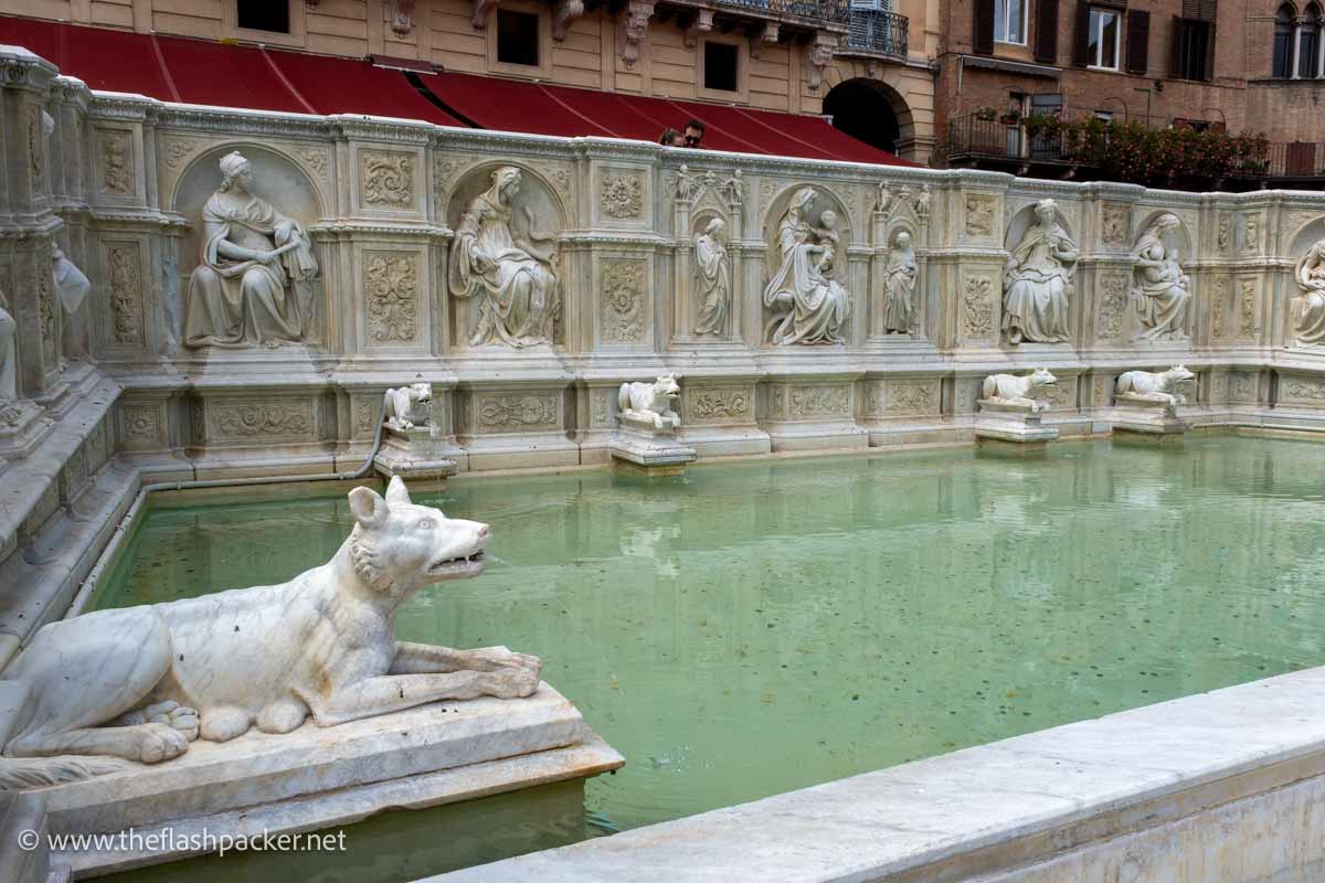 ornate stone rectangular fountain with carved animal figures and classical statues