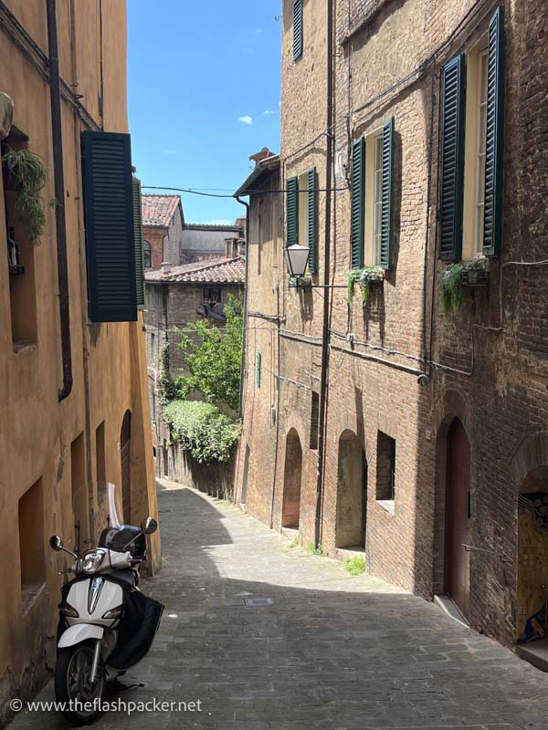 scooter in a narrow sloping street in siena italy