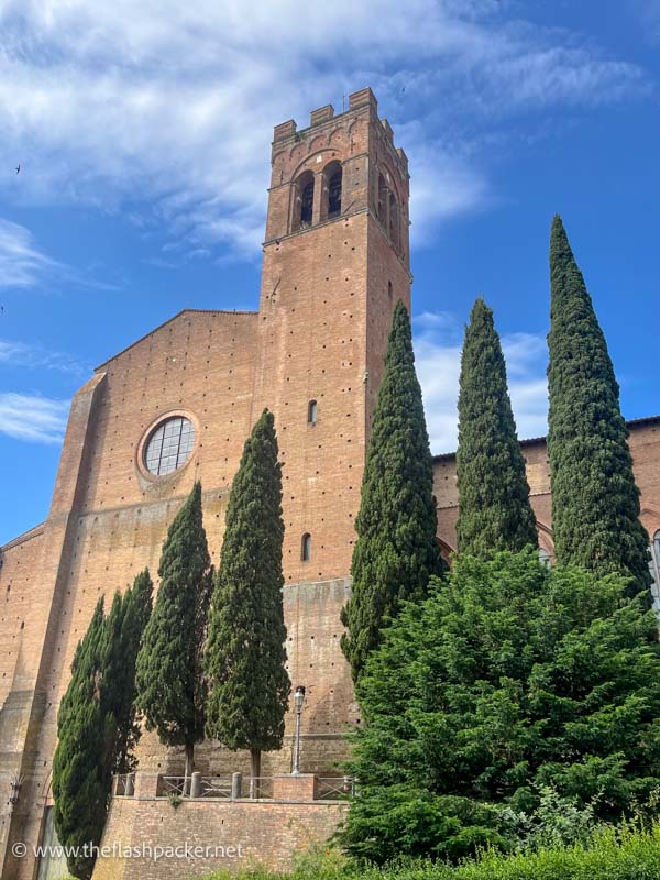 red brick exterior of large basilica with bell tower