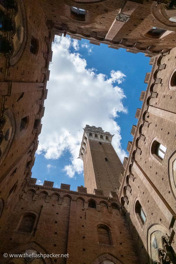 clock tower seen through a crenelated rectangular courtyard