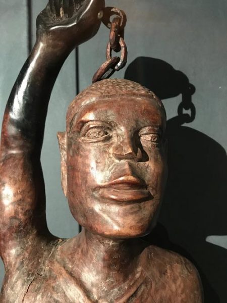 wooden sculpture of an african slave with cahin