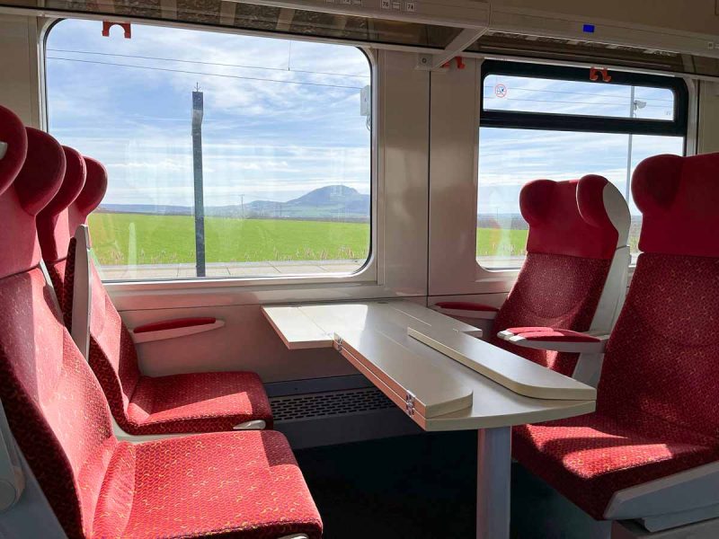 4 red seats around a table on a train from brno to kopice