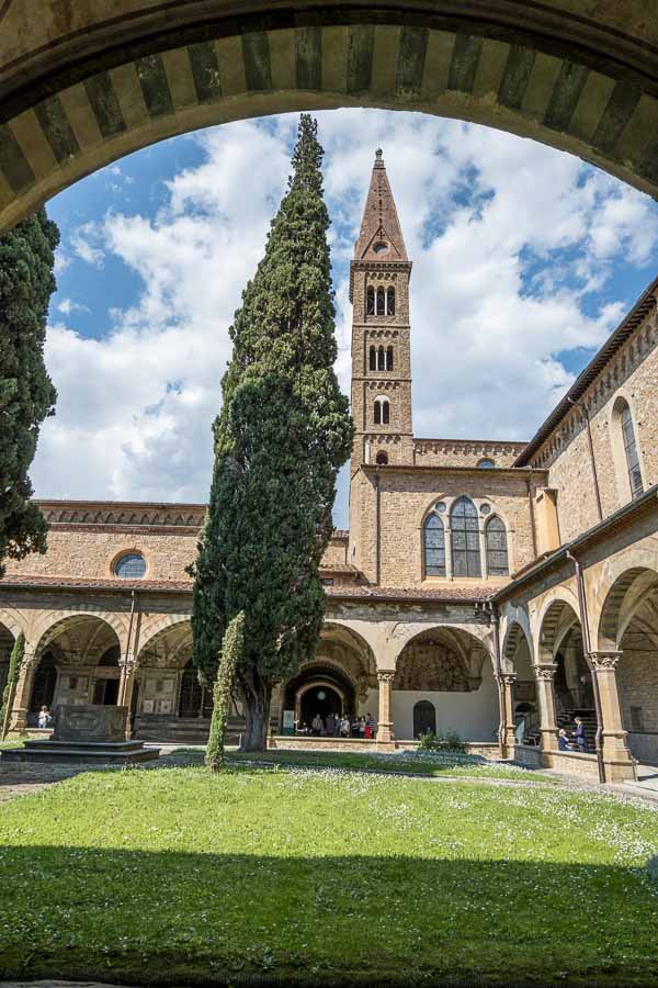 cloister with lawn and cypress tree and church tower