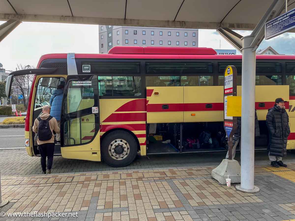 people boarding a yellow and red bus