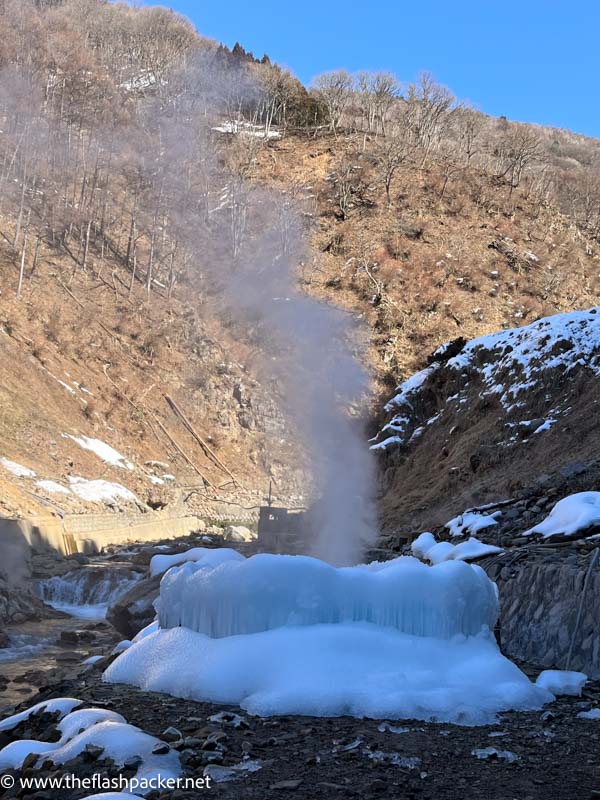 steam spouting out of a snow covered geyser