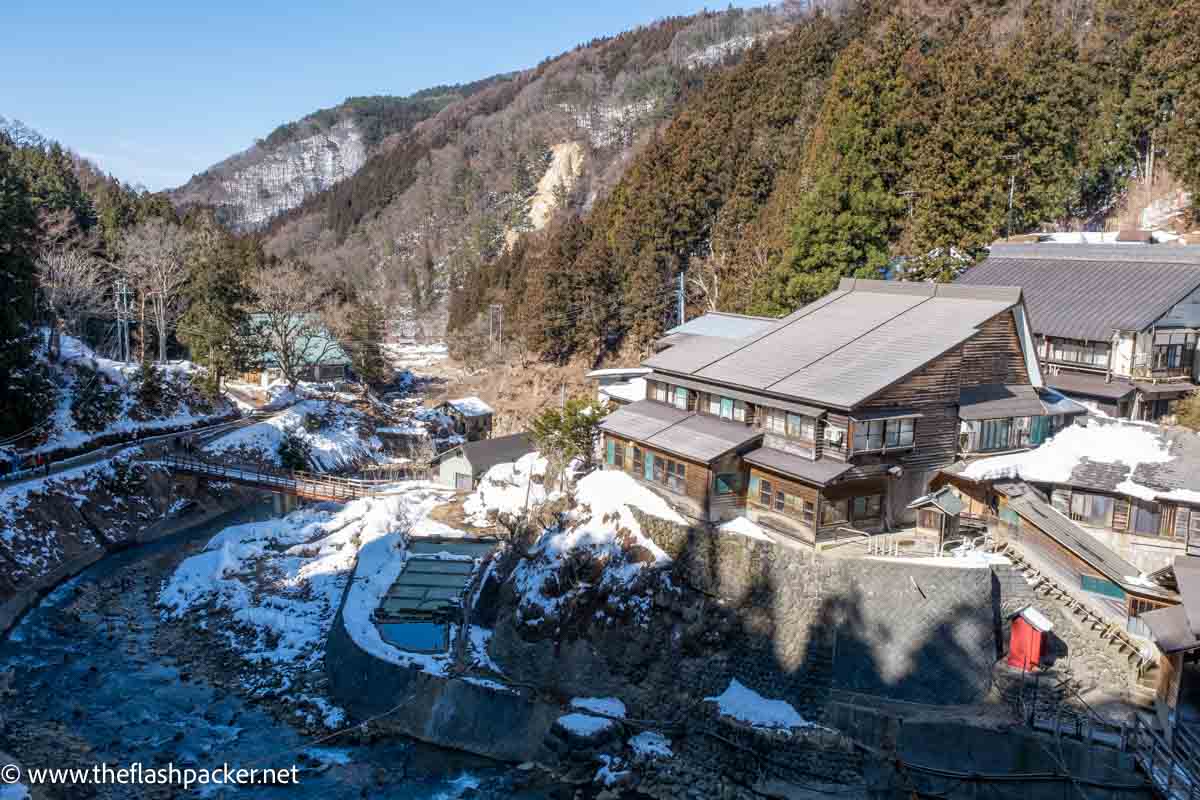 wooden buildings next to a snowy river gorge