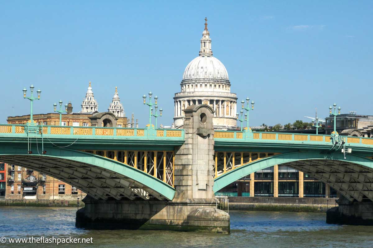 yellow and green bridge in front of cathedral dome