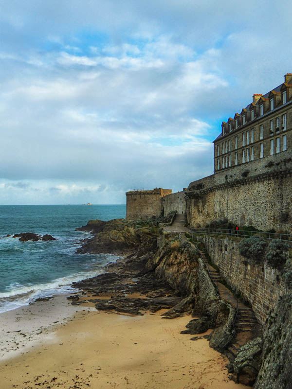 buildings of st malo in france hugging a small beach and rugged coastline