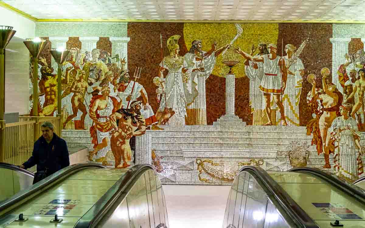 man in escalator in Sportivnaya station, St. Petersburg with background mosaic